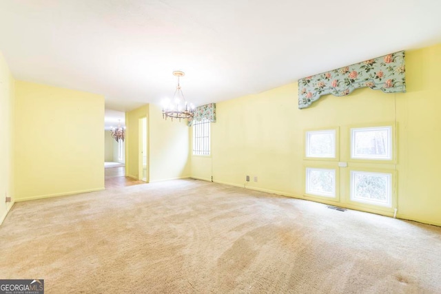 empty room featuring carpet, a wealth of natural light, and a chandelier