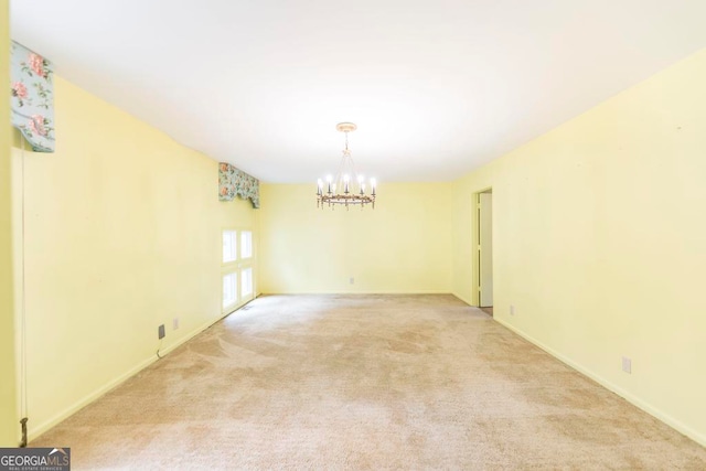 empty room featuring light carpet and an inviting chandelier