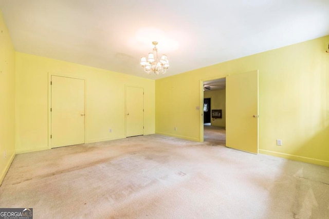 carpeted spare room featuring an inviting chandelier