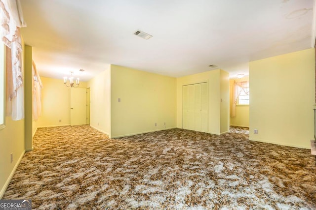 empty room featuring carpet and a notable chandelier