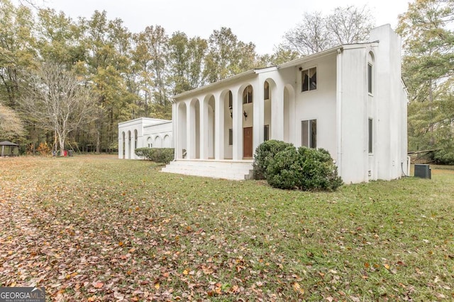 rear view of house featuring cooling unit and a lawn