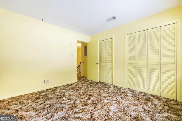 unfurnished bedroom with multiple closets and carpet