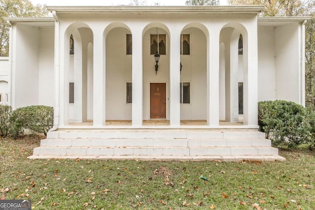 doorway to property with a lawn and covered porch