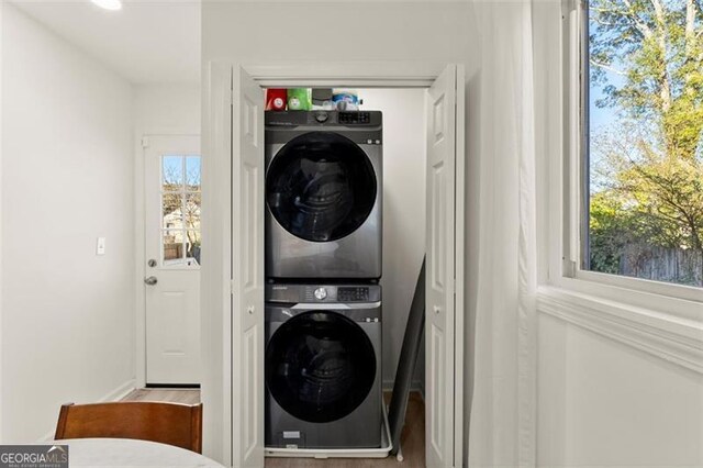 clothes washing area with stacked washing maching and dryer