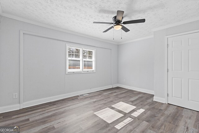 spare room with wood-type flooring, a textured ceiling, and ornamental molding