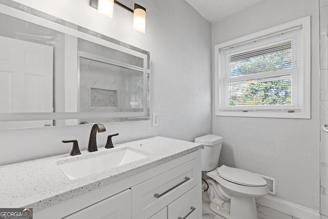 bathroom with vanity, toilet, and a shower with shower door