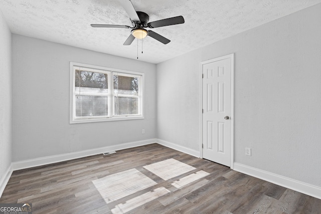 unfurnished room featuring dark hardwood / wood-style floors, ceiling fan, and a textured ceiling