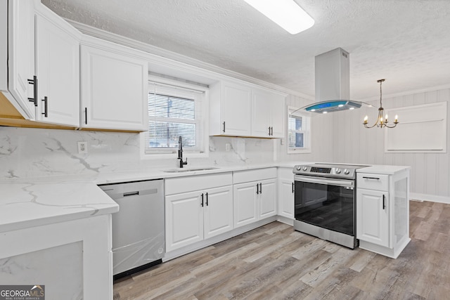 kitchen with sink, kitchen peninsula, decorative light fixtures, island range hood, and appliances with stainless steel finishes