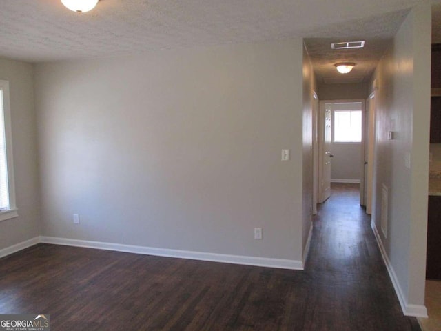 unfurnished room with a textured ceiling and dark hardwood / wood-style flooring