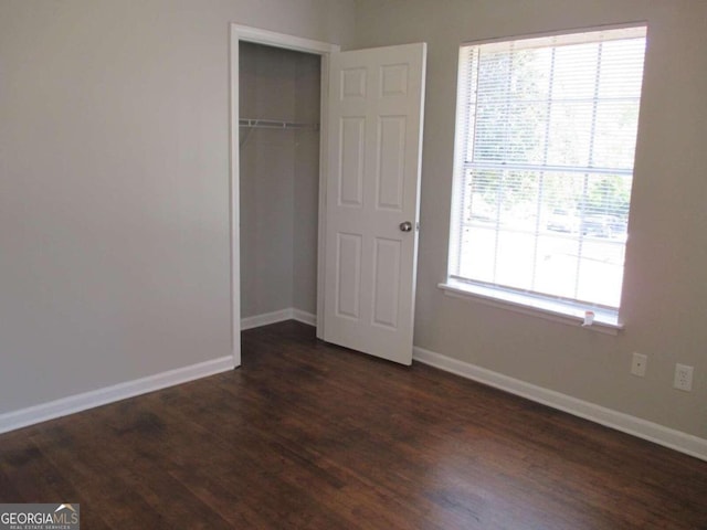 unfurnished bedroom featuring a closet, dark hardwood / wood-style flooring, and multiple windows