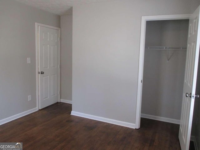 unfurnished bedroom featuring a textured ceiling, a closet, and dark hardwood / wood-style floors