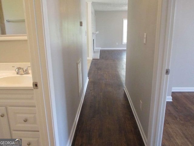 hallway with dark hardwood / wood-style flooring, sink, and a textured ceiling