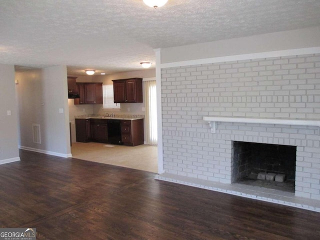 unfurnished living room featuring a fireplace, dark wood-type flooring, and a textured ceiling