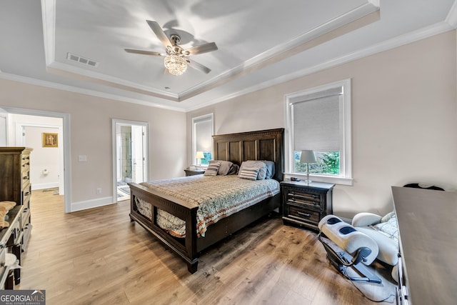 bedroom with a tray ceiling, ceiling fan, crown molding, and light hardwood / wood-style flooring