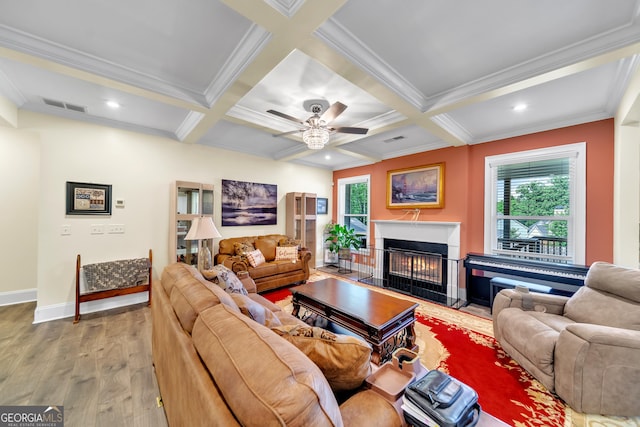 living room with coffered ceiling, ceiling fan, light wood-type flooring, ornamental molding, and beamed ceiling