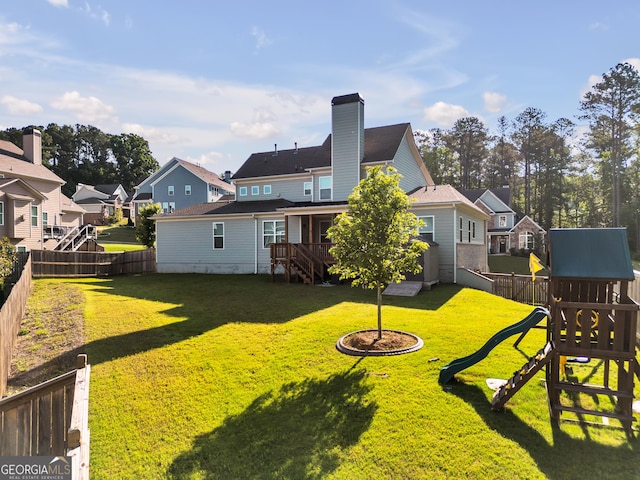 rear view of property with a yard and a playground