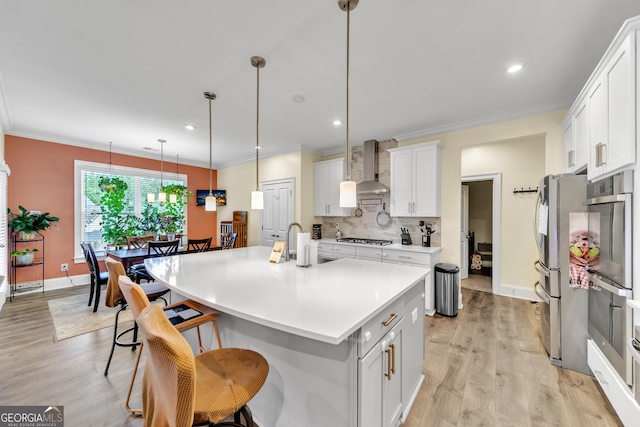 kitchen featuring white cabinetry, a kitchen island with sink, decorative light fixtures, decorative backsplash, and appliances with stainless steel finishes