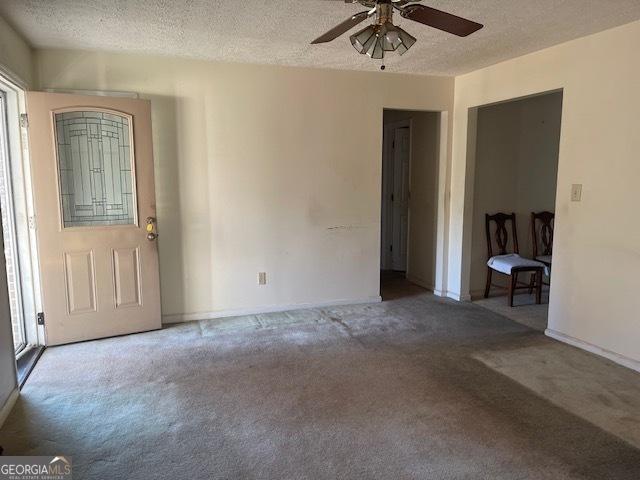 carpeted spare room featuring ceiling fan and a textured ceiling