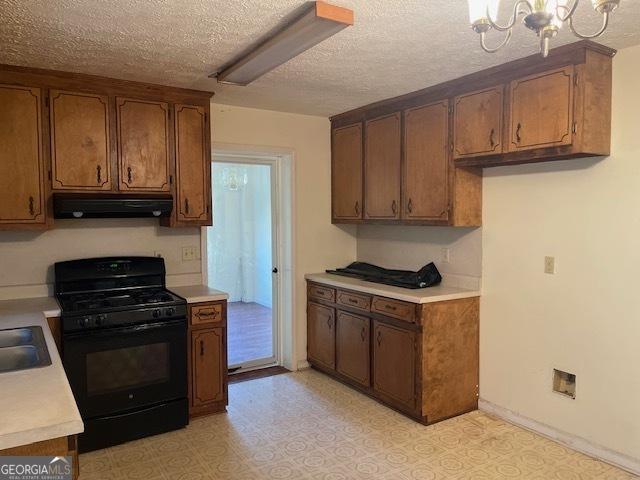 kitchen featuring sink, black gas stove, a textured ceiling, and a notable chandelier