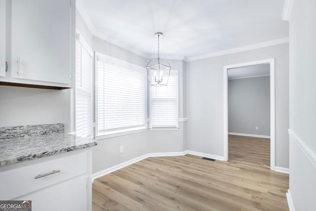 unfurnished dining area with ornamental molding, light wood-type flooring, and a notable chandelier