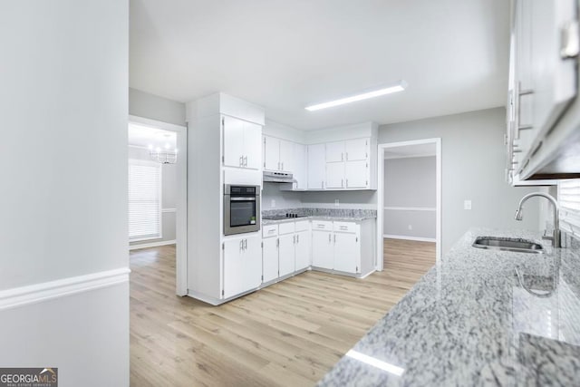 kitchen featuring sink, light hardwood / wood-style flooring, stovetop, oven, and white cabinets