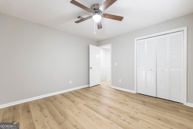 unfurnished bedroom featuring ceiling fan, a closet, and light wood-type flooring