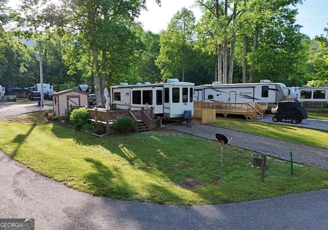 view of front of house featuring a front lawn, a storage unit, and a deck