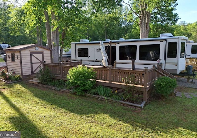 rear view of house with a lawn, a shed, and a wooden deck