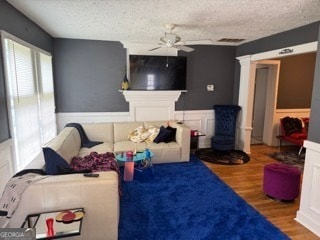 living room featuring ceiling fan, a textured ceiling, and hardwood / wood-style flooring