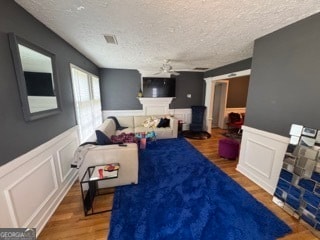 living room featuring hardwood / wood-style floors, a textured ceiling, and ceiling fan