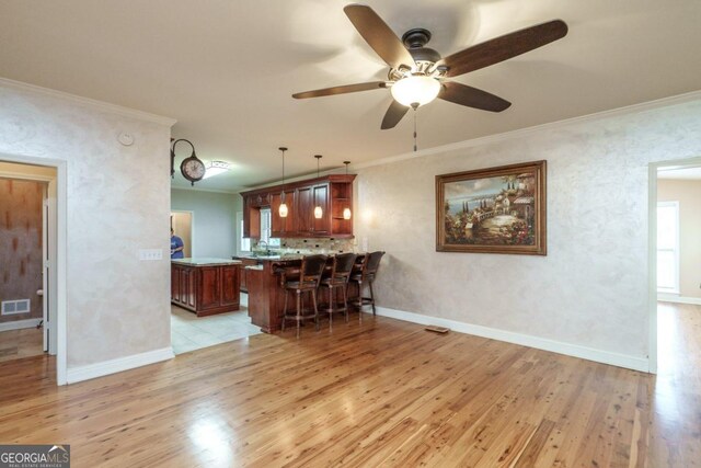 2505 Westchester Way, Conyers, GA 30013 - kitchen with light wood-type flooring, a kitchen breakfast bar, ceiling fan, a peninsula, and ornamental molding