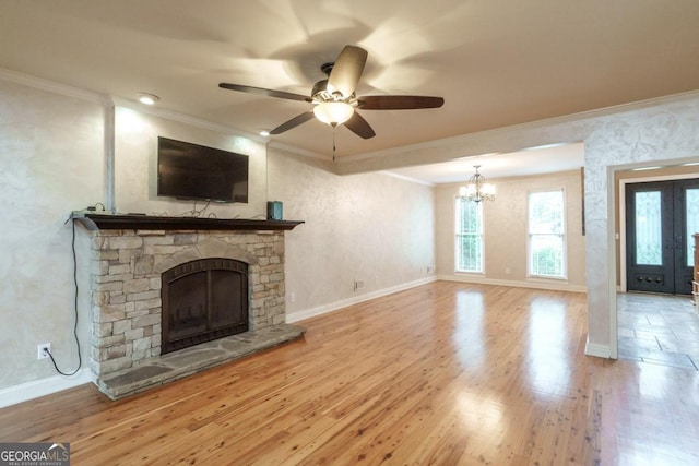 unfurnished living room with a stone fireplace, light hardwood / wood-style floors, ceiling fan with notable chandelier, and ornamental molding