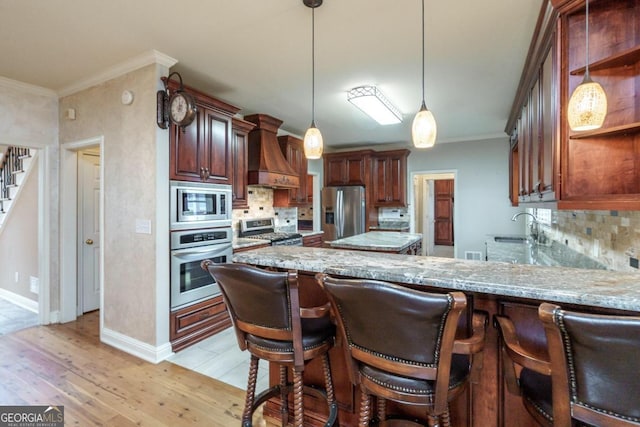 kitchen featuring pendant lighting, premium range hood, light hardwood / wood-style flooring, tasteful backsplash, and stainless steel appliances