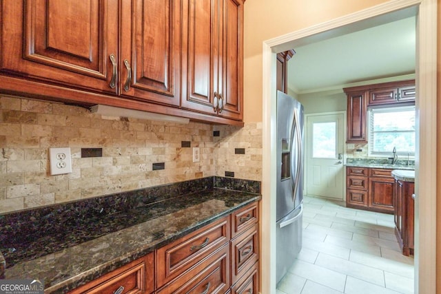 kitchen featuring sink, tasteful backsplash, stainless steel fridge with ice dispenser, dark stone counters, and ornamental molding