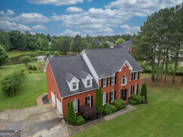 2505 Westchester Way, Conyers, GA 30013 - view of front facade with a water view, concrete driveway, a front lawn, brick siding, and roof with shingles