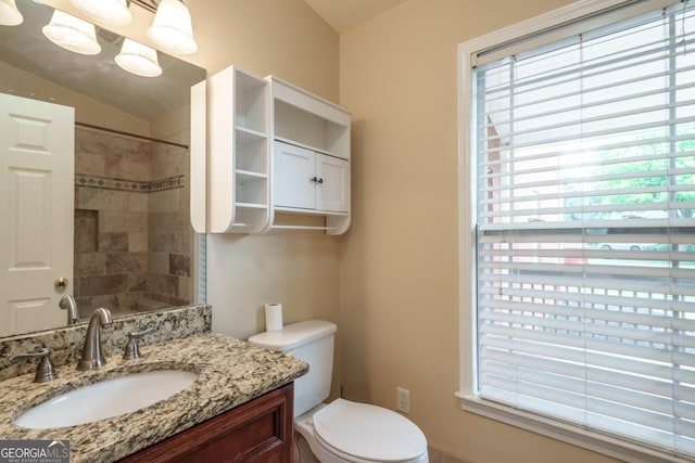 bathroom featuring vanity, a tile shower, vaulted ceiling, and toilet