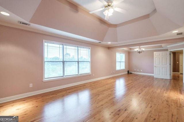 unfurnished room featuring ceiling fan with notable chandelier, a raised ceiling, and light hardwood / wood-style flooring