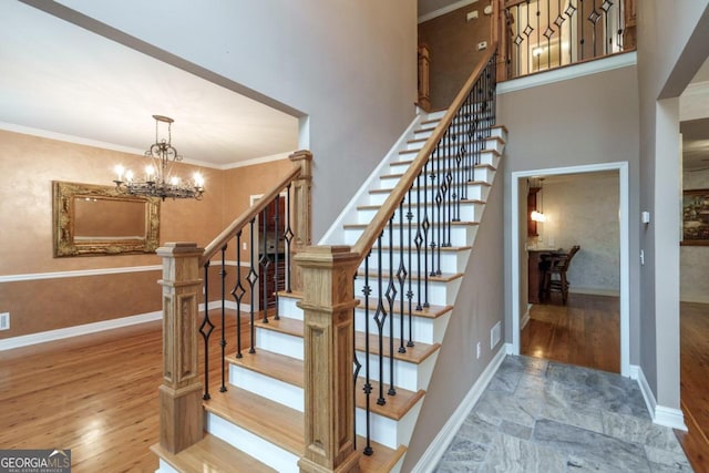 stairs with hardwood / wood-style flooring, ornamental molding, and a chandelier