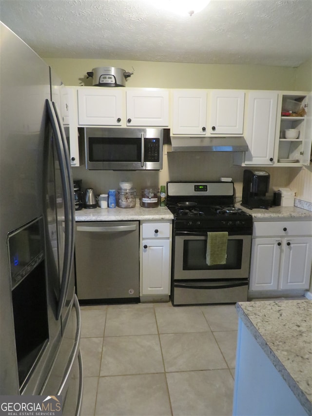 kitchen featuring light tile patterned floors, a textured ceiling, stainless steel appliances, and white cabinetry