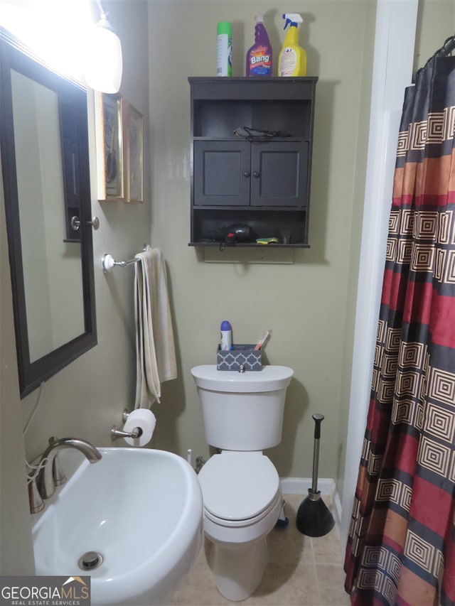 bathroom featuring a shower with curtain, toilet, sink, and tile patterned flooring