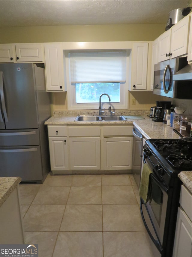 kitchen featuring white cabinetry, sink, a textured ceiling, light tile patterned floors, and appliances with stainless steel finishes