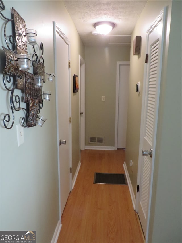 hallway featuring light hardwood / wood-style flooring and a textured ceiling