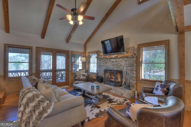 living room featuring a healthy amount of sunlight, wood-type flooring, a fireplace, and high vaulted ceiling