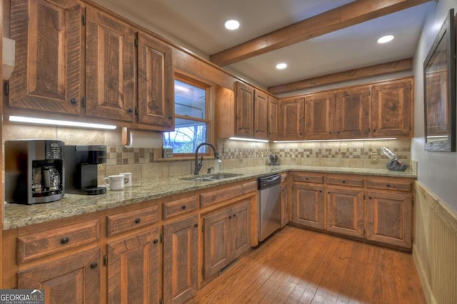 kitchen featuring light stone countertops, decorative backsplash, light wood-type flooring, stainless steel dishwasher, and sink