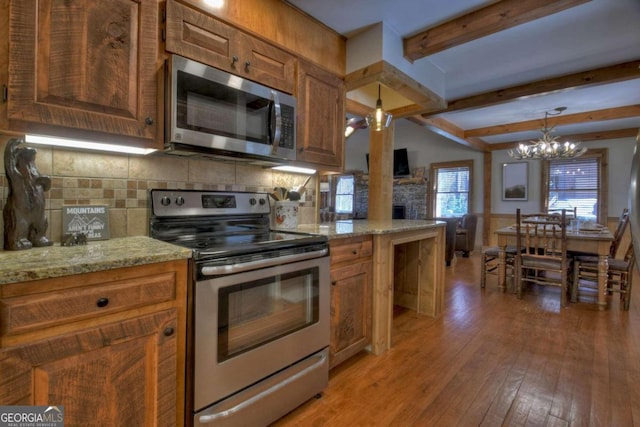 kitchen featuring a chandelier, decorative light fixtures, decorative backsplash, appliances with stainless steel finishes, and light wood-type flooring