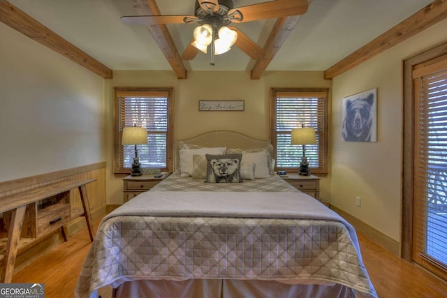 bedroom with ceiling fan, beamed ceiling, and light wood-type flooring