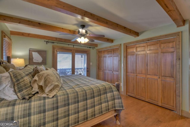 bedroom featuring ceiling fan, beam ceiling, light wood-type flooring, and multiple closets