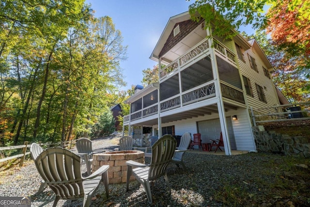 back of property with a fire pit, a sunroom, a garage, and a patio