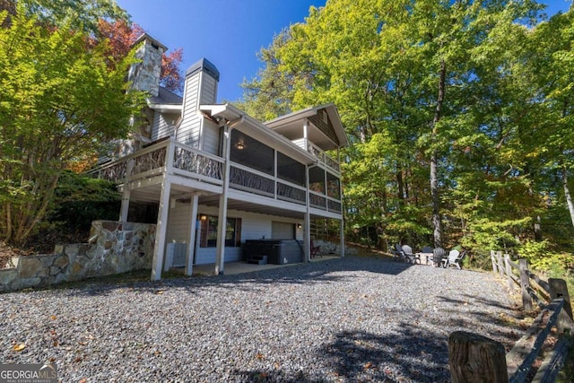 back of property featuring a hot tub, a patio area, and a sunroom