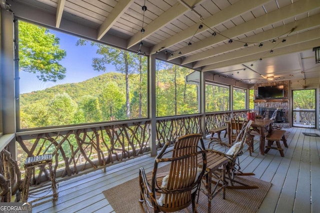 sunroom with beam ceiling, a mountain view, and wooden ceiling